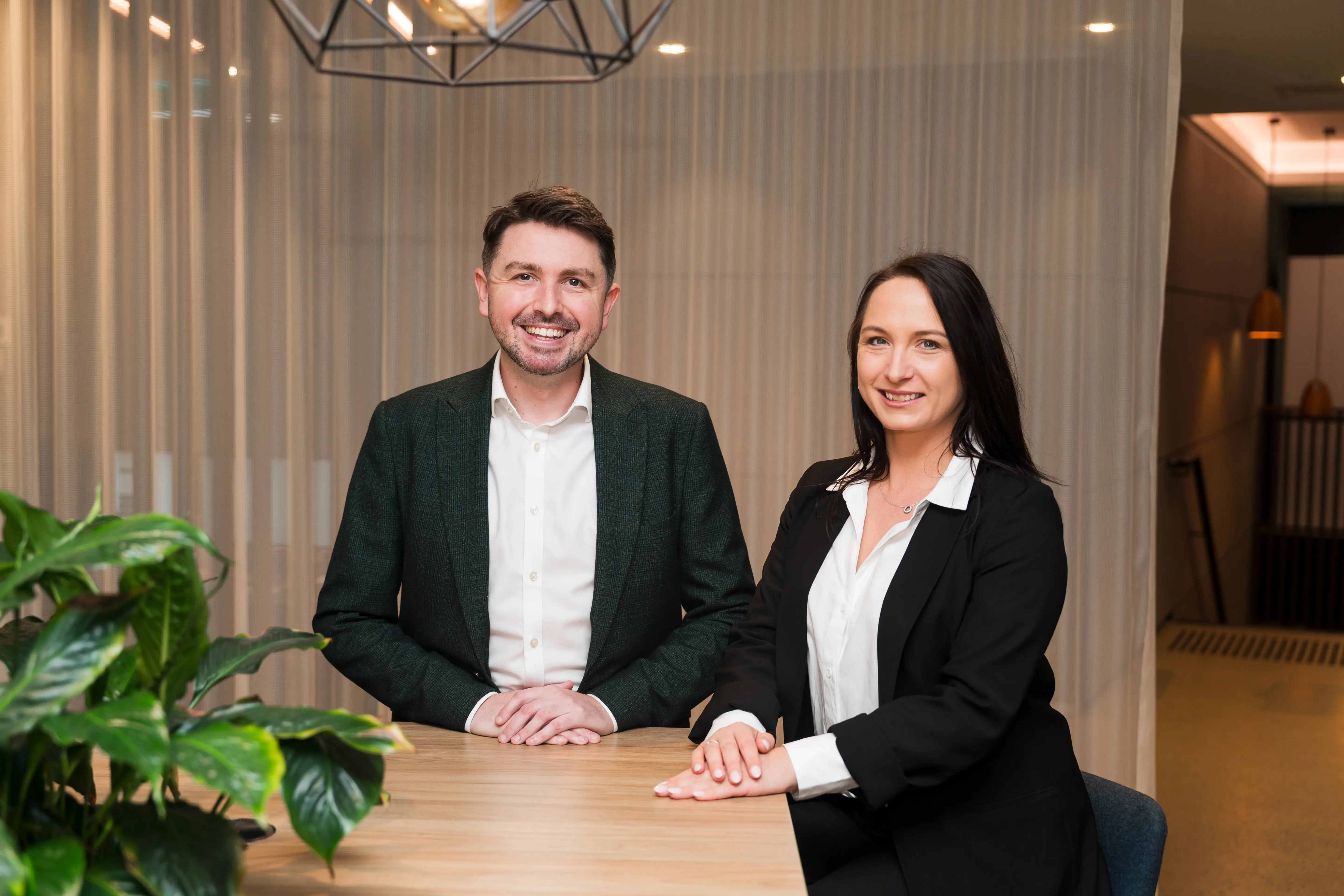 Tom and Samantha smiling at desk